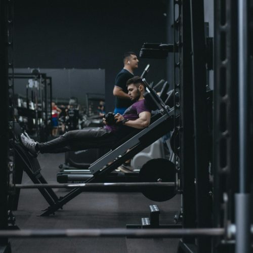 A man working out on a leg press machine surrounded by gym equipment.