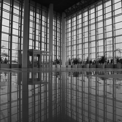 Spacious modern atrium with glass walls and polished reflections, exuding an urban architectural style.