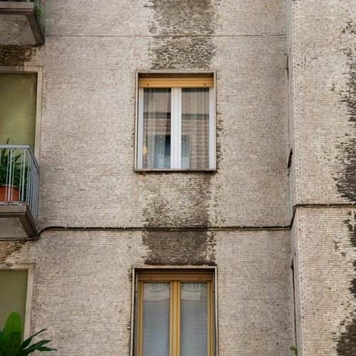 Detailed view of a vintage residential building's facade with balconies and windows, showcasing urban architecture.