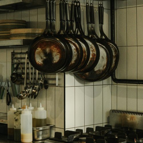 An industrial kitchen setup featuring hanging pans and a modern stove in Ankara, Türkiye.