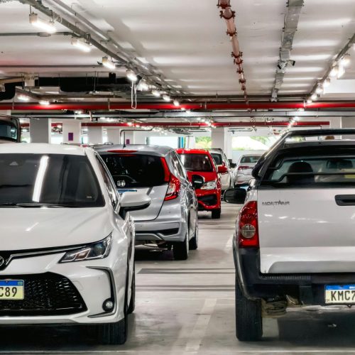 A busy underground parking lot filled with various cars lined up in designated spots.