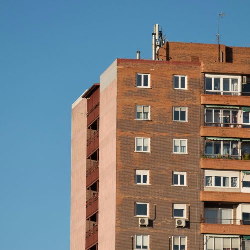 Facade of a modern apartment building against a clear blue sky in Madrid, Spain.
