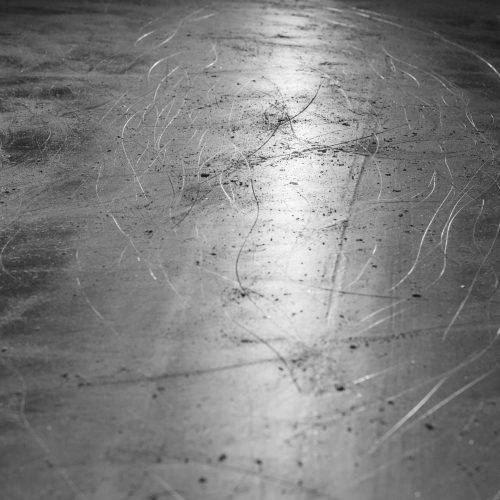 Black and white photo capturing scratched surface texture of an ice rink.