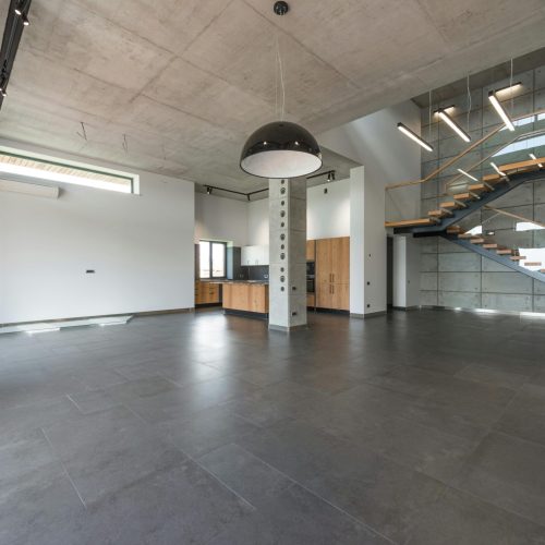 Modern loft style home interior design of spacious hallway with gray stone floor and stairway in contemporary minimalist luxury house