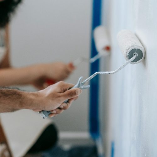 Couple painting a wall with rollers, perfect for home improvement and renovation themes.